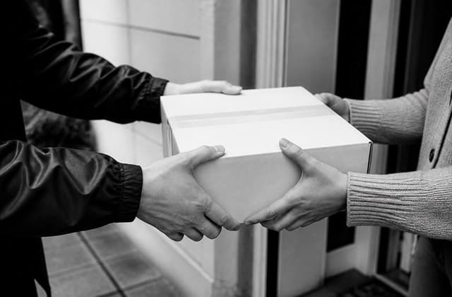 A sealed parcel being handed from a courier to its recipient