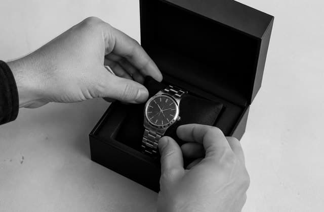 Hands packing a stainless-steel watch into a presentation box