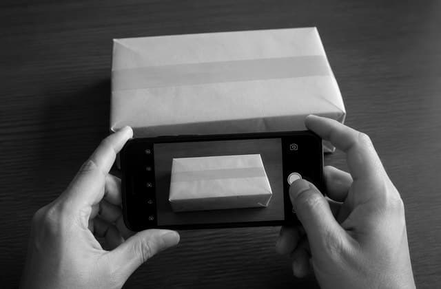 A buyer recording an intact sealed parcel with a phone before opening